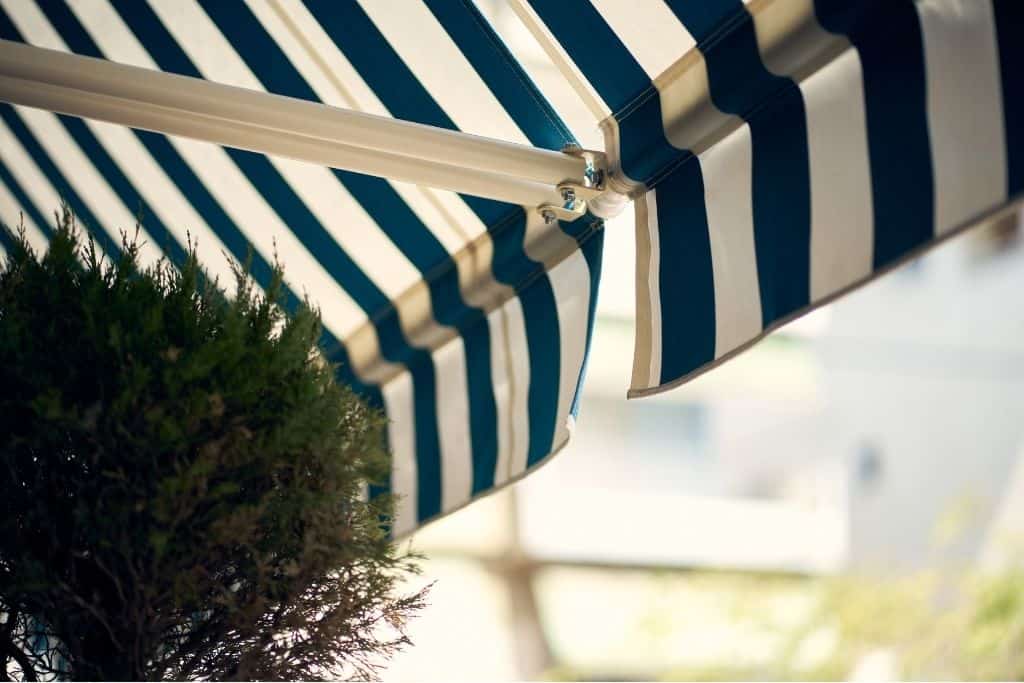 Toldo azul-blanco en jardín de Montequinto